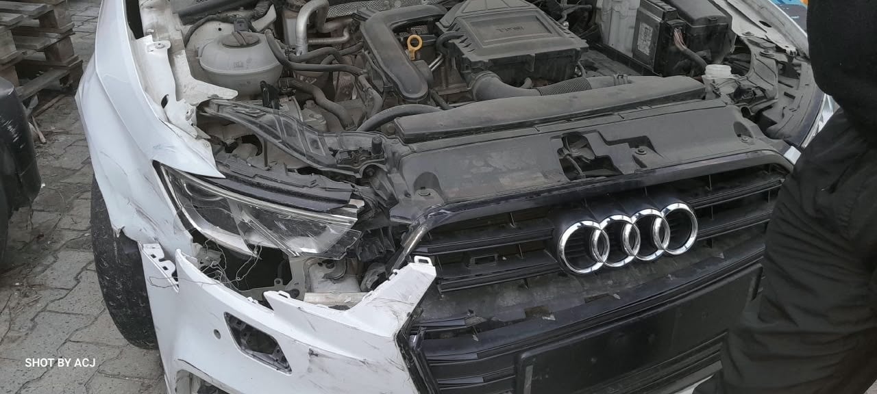 White Audi exposed front damage with hood removed before repair
